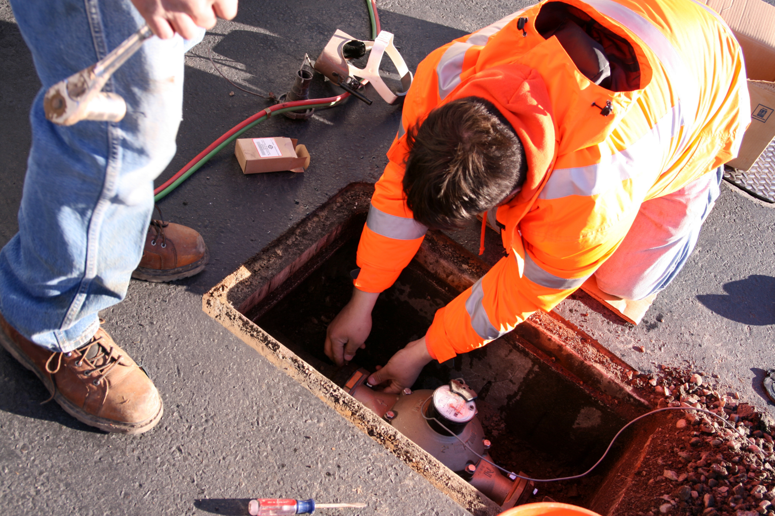 Workers installing new meters in street water meter box