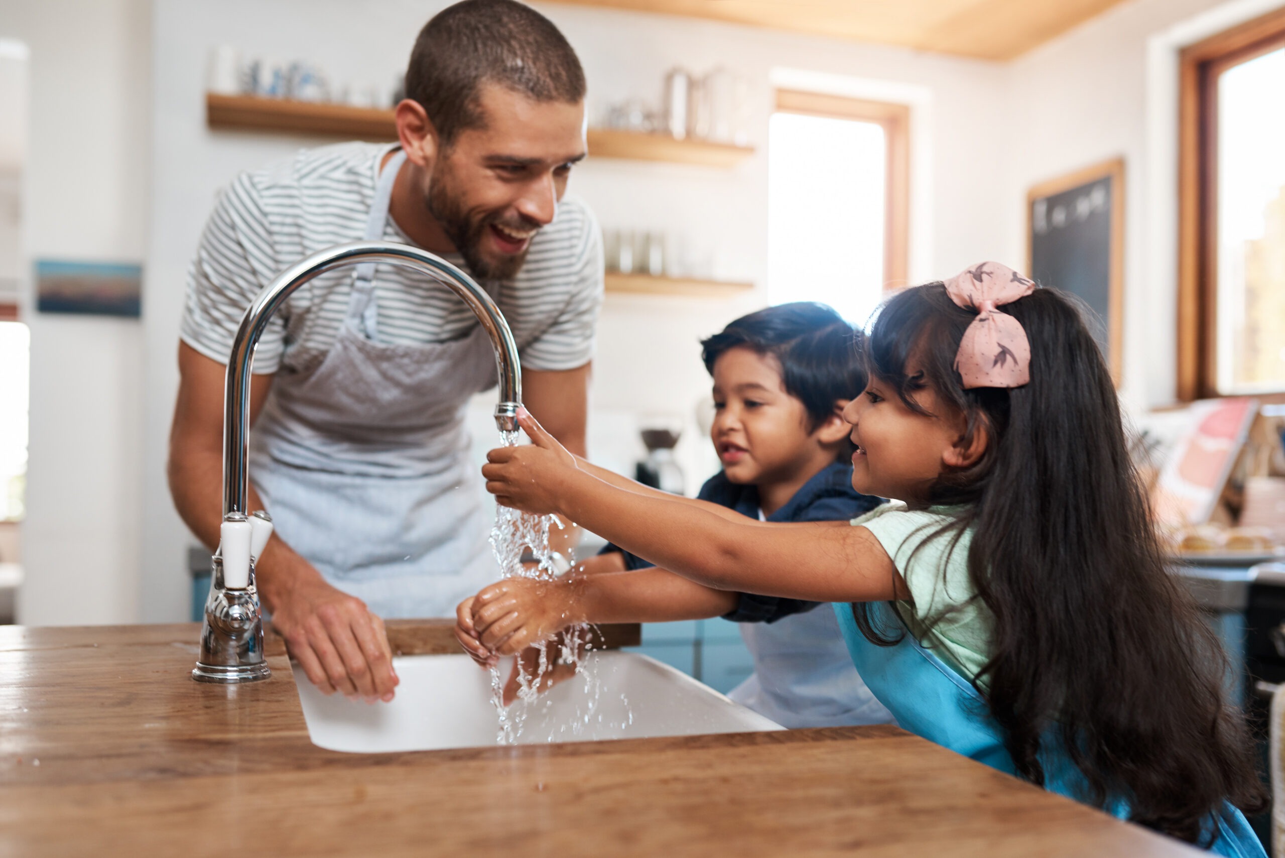 Family washing their hands together in the kitchen sink
